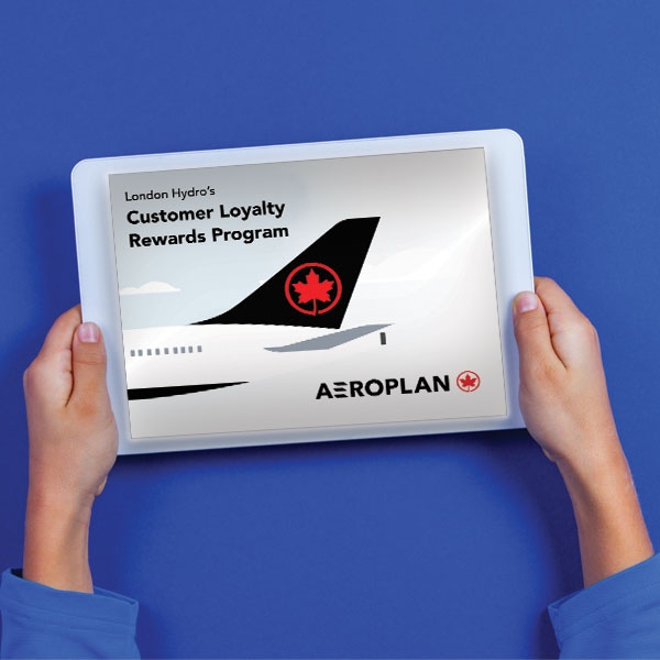 Hands holding an iPad showing the back end of an airplane promoting Aeroplan