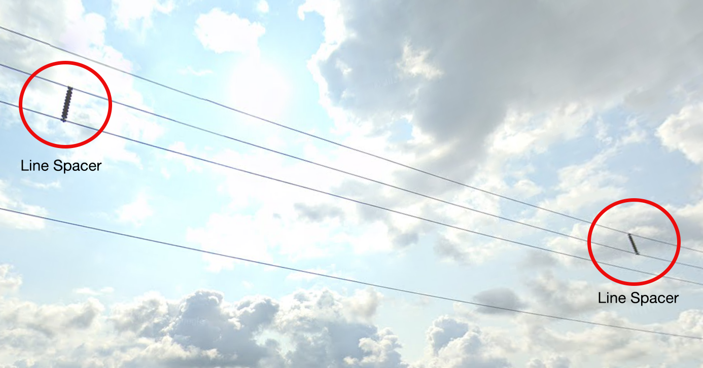 Power lines in the sky with line spacers separating lines that are prone to swinging (galloping) in strong winds